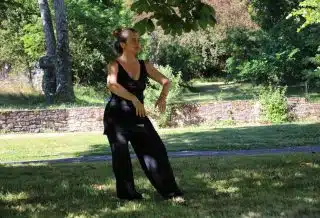 woman in black tank top and black pants standing on green grass field during daytime